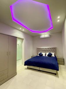 利雅德شاليه الماسيه خاص و مميز بأحدث المواصفات لنصنع الجمال بعينه的一间卧室配有蓝色的床和紫色天花板