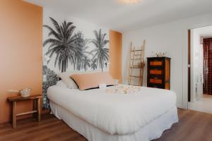 比亚里茨Hôtel PALMITO的卧室配有一张白色大床,墙上挂着棕榈树