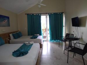 蓬塔露奇亚Paradise Island Beach Resort的客房设有两张床、一张桌子和电视。