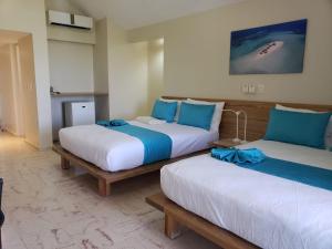 蓬塔露奇亚Paradise Island Beach Resort的两张睡床彼此相邻,位于一个房间里