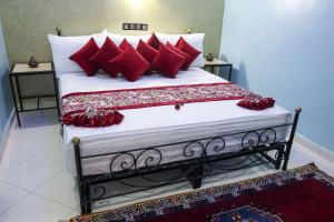 ZeïdaHOTEL LA POMME ZAIDA的一间卧室配有一张带红色枕头的大床