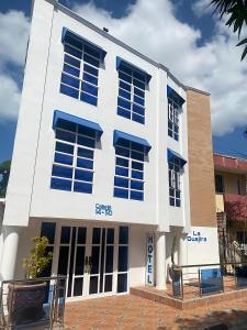 里奥阿查Hotel La Guajira的白色的建筑,边有蓝色的窗户