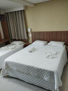 嘎林海斯港Pousada Casarão do Porto - Porto de Galinhas PE的酒店客房,配有两张带白色床单的床