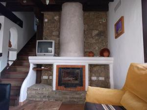 贝纳卢普-卡萨斯维耶哈斯CASA HUGANA的客厅设有石制壁炉和电视