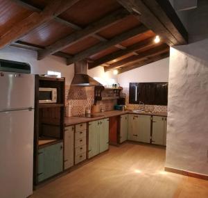 贝纳卢普-卡萨斯维耶哈斯CASA HUGANA的厨房配有白色冰箱和木制橱柜。