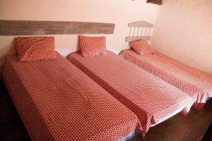 贝纳卢普-卡萨斯维耶哈斯CASA HUGANA的一间红色蚊帐的房间的三张床