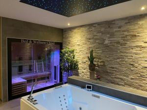 圣安娜兰Bed & Wellness Chinel Luxe vakantiehuis met Sauna's en Bubbelbad的砖墙客房内的浴缸