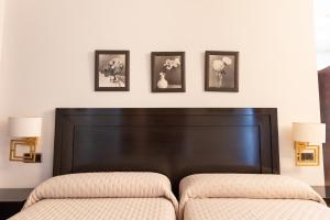 马尔莫莱霍广场旅馆的一间卧室配有床头板,墙上有三幅画
