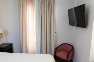 马尔莫莱霍广场旅馆的酒店客房配有一张床、一把椅子和一台电视。