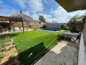 拉塞雷纳Casa de totys en la Serena的一个带草坪和雨伞的小后院