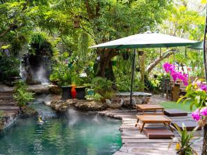 呵叻Crystal Resort Korat的一个带遮阳伞和瀑布的游泳池