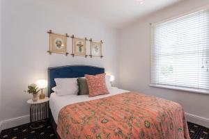 朗塞斯顿Two Worlds Townhouse的一间卧室配有一张带橙色毯子和窗户的床。