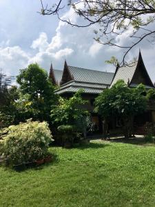 三帕兰MrT Riverside Sampran มิสเตอร์ที โฮมสเตย์-ช้องนาง的一座带绿树和灌木的庭院的房子