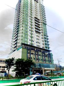 宿务Across Sm City Cebu Sunvida Tower Studio Unit的一座高大的建筑,前面有一辆汽车