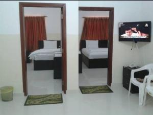 苏尔Al Basateen Hotel Apartment的一间卧室设有两张床、一台电视和镜子
