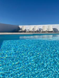 拉奥利瓦Villa Verano Apartamentos Compartidos Villaverde的一个带椅子的游泳池,海水蓝色