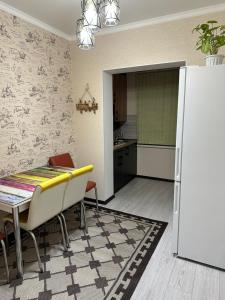 奇姆肯特Двухкомнатная квартира的厨房配有桌子和白色冰箱。