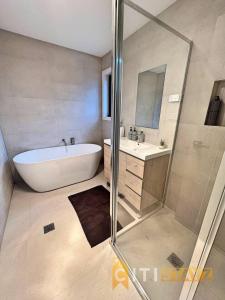 LyonsLavish in Lyons - 3bd 2bth Spacious & Modern Home的带浴缸、水槽和淋浴的浴室