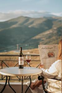 卡拉维塔阿内拉德酒店的坐在桌子旁的女人,拿着一瓶葡萄酒和一杯