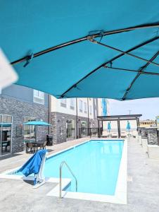JenksCandlewood Suites - Tulsa Hills - Jenks, an IHG Hotel的一个带蓝伞和桌椅的游泳池