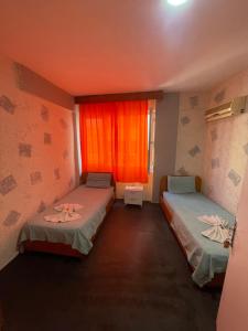 安塔利亚Ersoy Ak Pansiyon的客房设有两张床和一个带橙色窗帘的窗户。