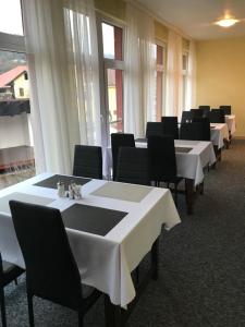 奥什恰德尼察凯瑟拉旅馆的一排桌子,上面有黑色的椅子和白色的桌布