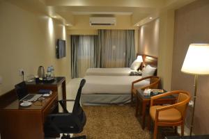 明亚Omar El Khayam Al Minya Hotel的酒店客房,配有一张床、一张桌子和椅子