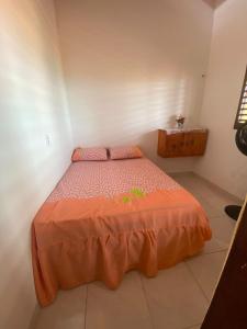 伊卡普伊Chalé da Kikia的一间卧室配有一张带橙色棉被的床