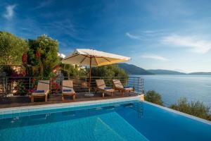 ÉvyirosIris Villas Lefkada - Marine Villa的水边的游泳池配有椅子和遮阳伞