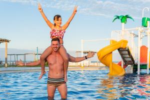 阿拉卡茹Makai Resort All Inclusive Convention Aracaju的站在水面上的人和一个女孩