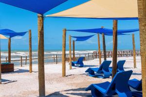 阿拉卡茹Makai Resort All Inclusive Convention Aracaju的海滩上摆放着蓝色的椅子和遮阳伞