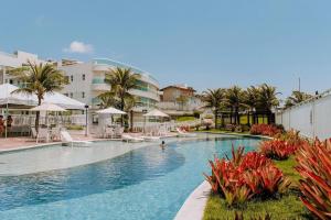 帕纳米林Qavi - Flat em Resort Beira Mar Cotovelo #InMare109的一座带椅子和棕榈树的游泳池以及建筑