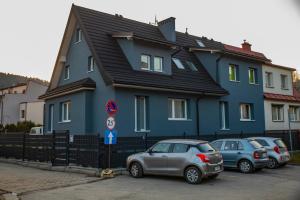 维斯瓦Apartamenty Wisła Centrum的一座蓝色的房子,前面有汽车停放