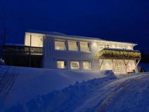 KvaløyaBeautiful view - close to the sea, mountains and nature的夜晚在雪中点亮的房子