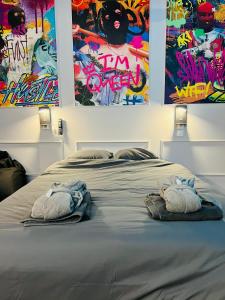 杜埃Capsule Street Art - Sauna- Jacuzzi - Playstation 5 - Billard - Netflix - Home cinéma - Terrasse的一间卧室配有一张床,上面有两条毛巾