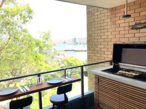 悉尼Manly family executive apartment的阳台配有烧烤架和桌椅。