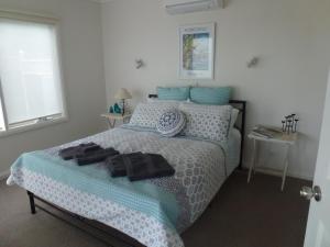 史密斯海滩灰雁@史密斯住宿加早餐旅馆的一间卧室配有一张带蓝色和白色床单及枕头的床。