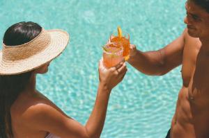 檀香山Wayfinder Waikiki的两个女人在泳池旁喝一杯