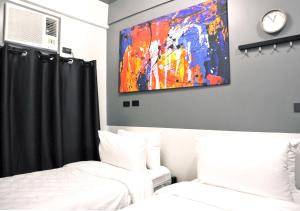 马尼拉mySTAY Hotel BGC West的一间卧室设有两张床,墙上挂着一幅画