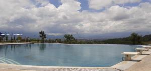玛琅The Valley Guesthouse的一座带长椅和云天的大型游泳池