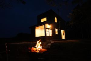 士别市小さな森の貸し切り宿Forest-House-Ranapirica的夜晚在房子前面烧火