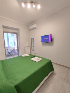 那不勒斯Apartment NAPOLI MARADONA的卧室配有一张绿色的床,墙上配有电视