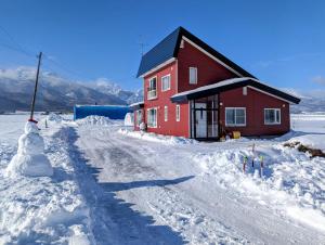 富良野All Seasons Furano Chalet的一位雪人站在红房子旁边