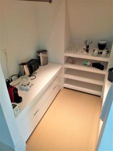 霍恩Kaap Hoorn Club Bed en Breakfast的厨房配有白色抽屉和带微波炉的架子。