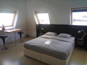 霍恩Kaap Hoorn Club Bed en Breakfast的一间卧室配有一张床、一张桌子和两个窗户