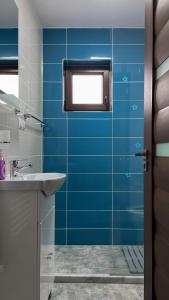 锡比乌Five House的蓝色瓷砖浴室设有水槽和窗户