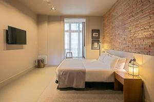 巴塞罗那Uma Suites Pau Claris的一间卧室设有一张大床和砖墙