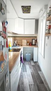 圣但尼Loft Saint-Denis/Porte de Paris的小厨房铺有木地板,配有白色橱柜。