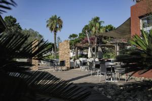 博尔戈Belambra Clubs Borgo - Pineto的庭院配有桌椅和棕榈树