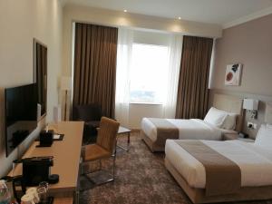 多哈Gloria Hotel & Suites Doha的酒店客房配有两张床和一张书桌